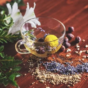 A cup of tea with herbs and nuts on the table.
